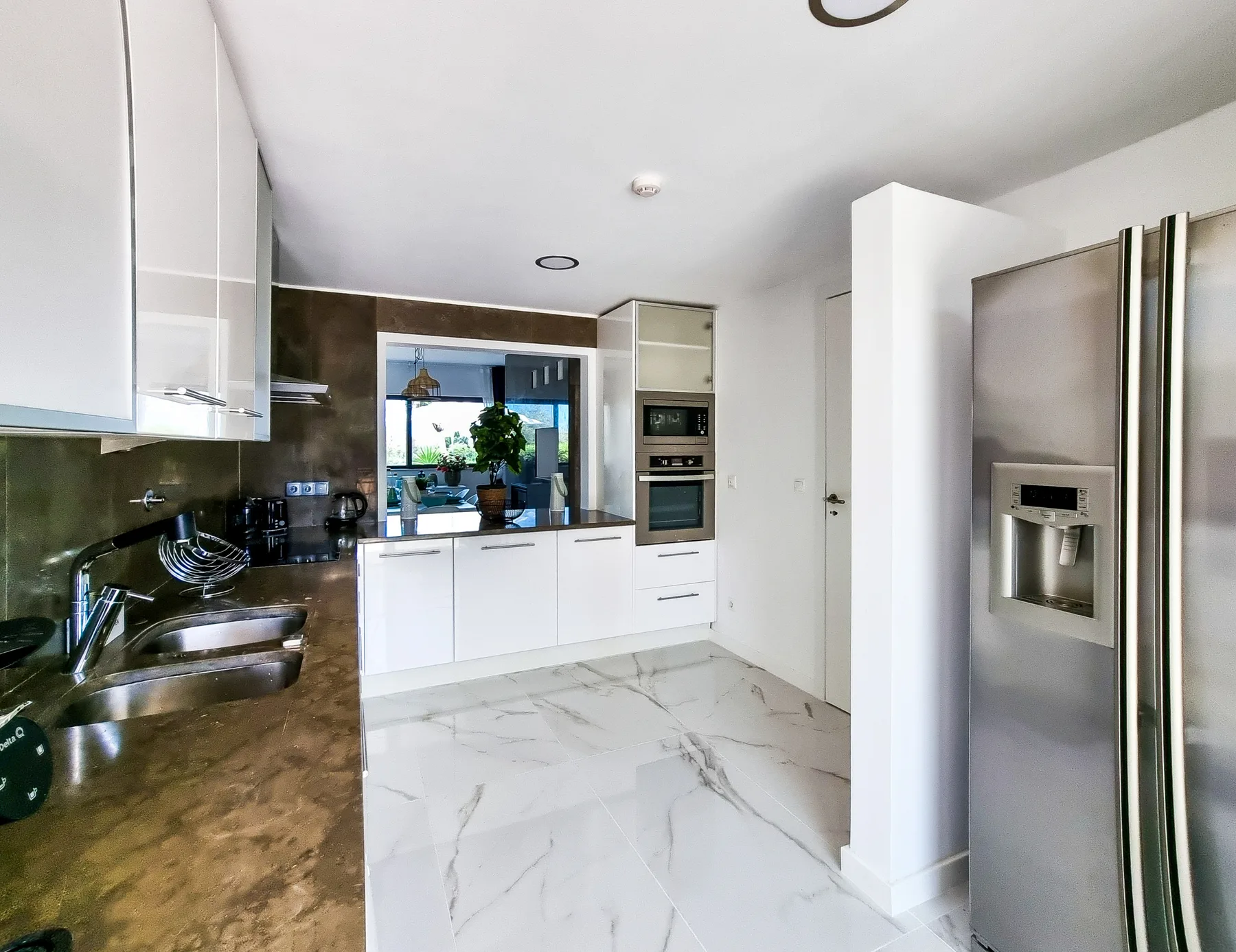 A modern kitchen with white cabinets, dark countertops, and stainless steel appliances.