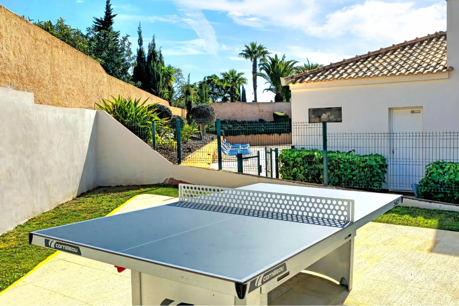 An outdoor recreation area with a table tennis table beside a small building.