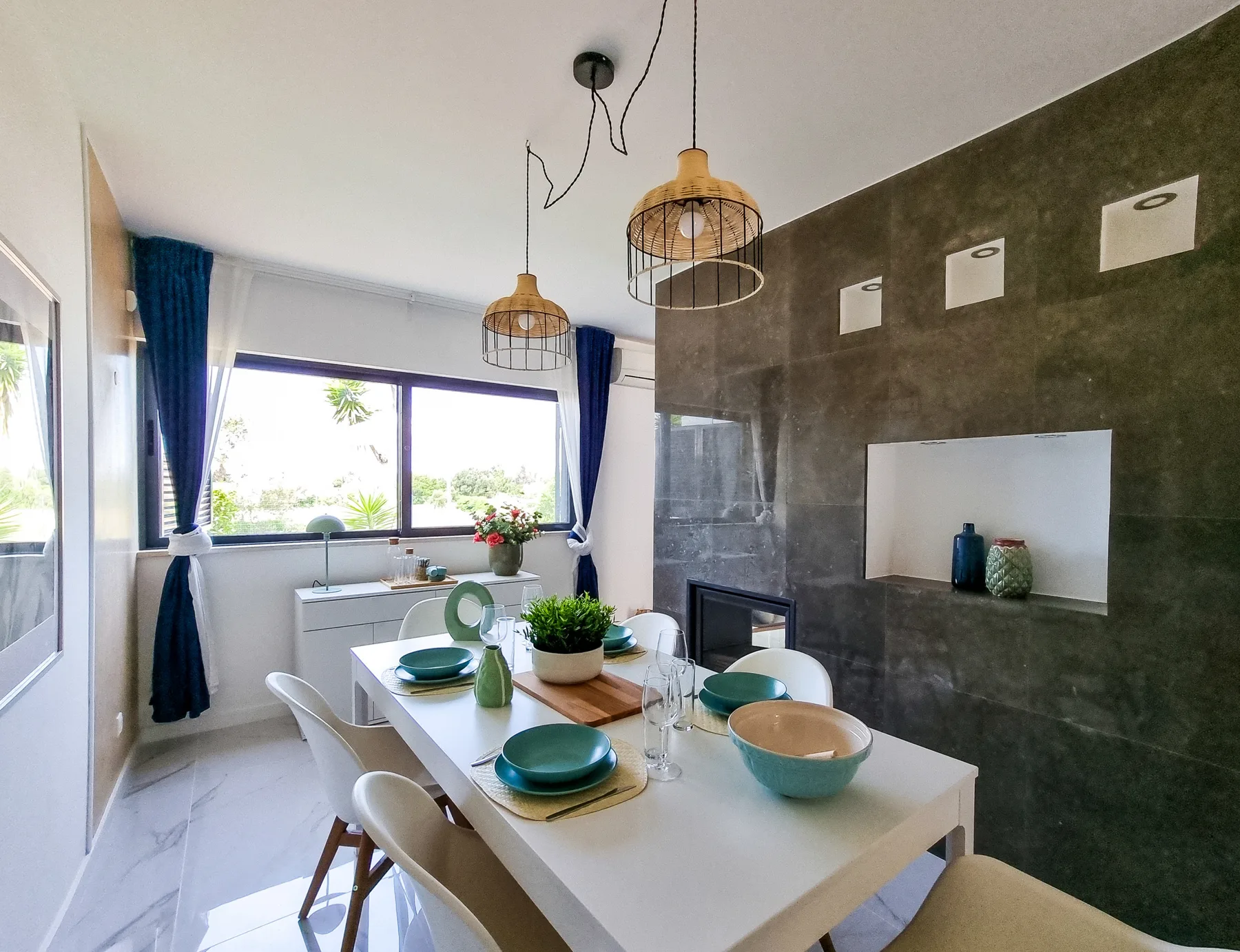A bright dining area with a long table beside a window.