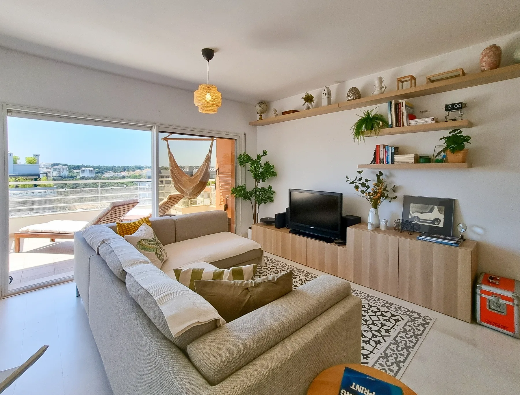 A bright living room with a sectional seating area and sliding glass doors to a balcony.