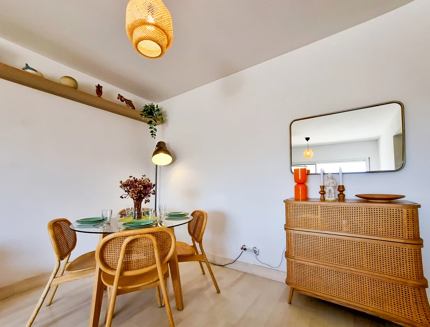 A dining area with a round table and woven seating beside a rattan cabinet.