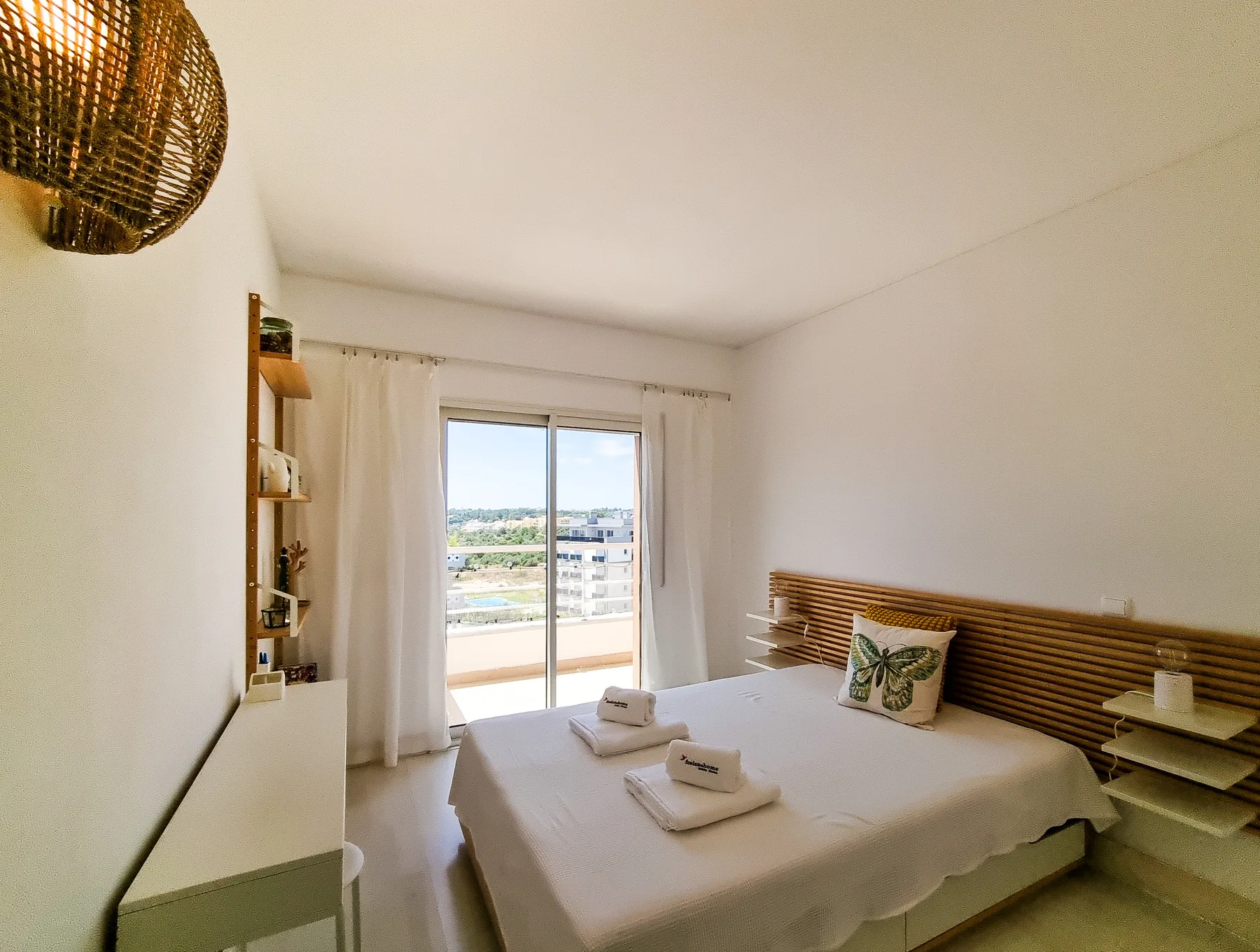 A bright bedroom with a bed and sliding glass doors opening onto a balcony.