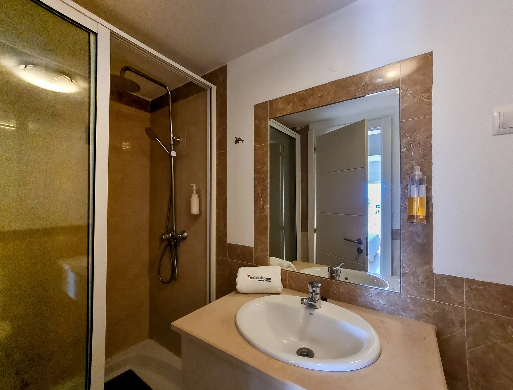 A bathroom with a sink, mirror, and shower.