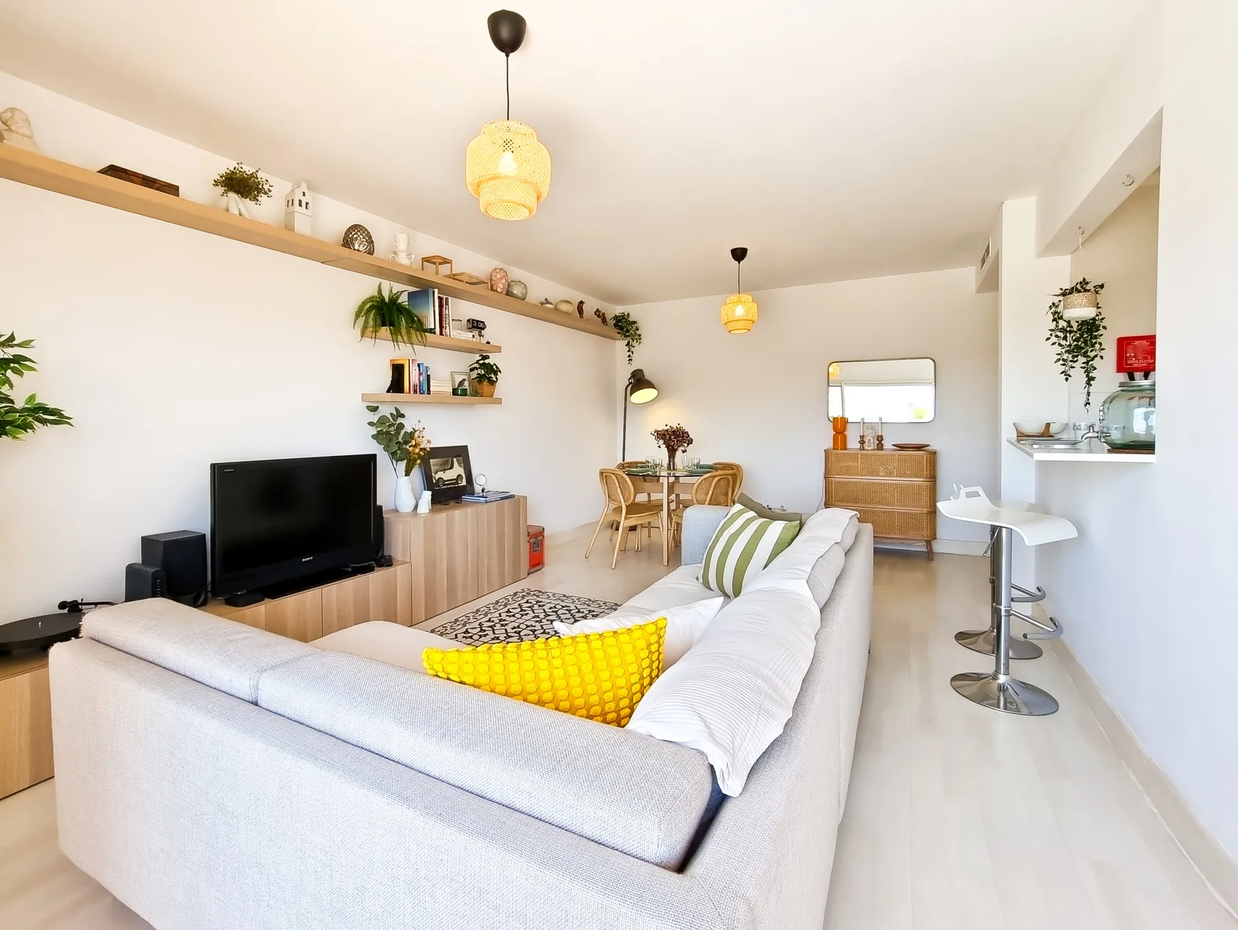 A bright living room with seating, a television, and a dining area.