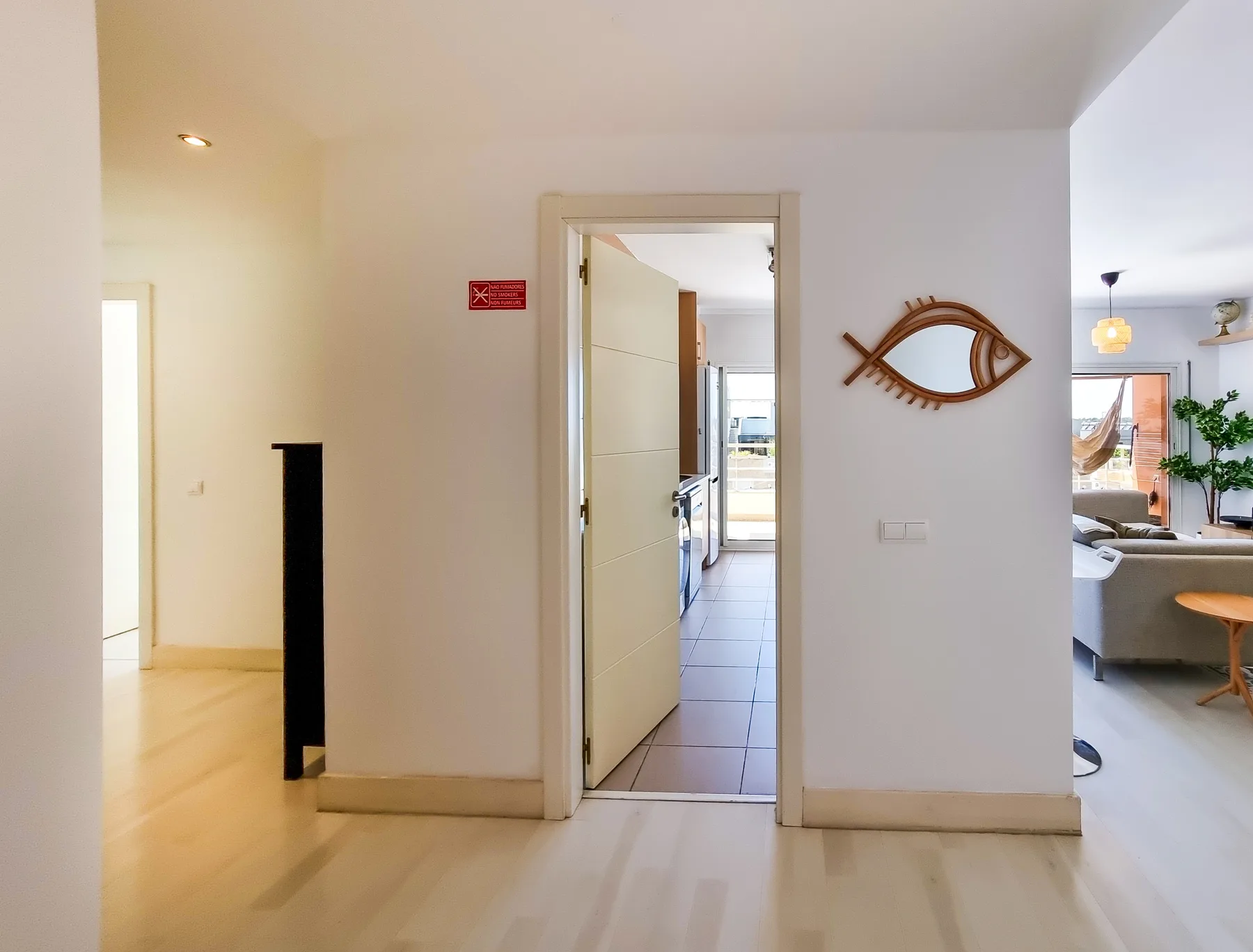A bright apartment hallway opens onto a kitchen and living area.