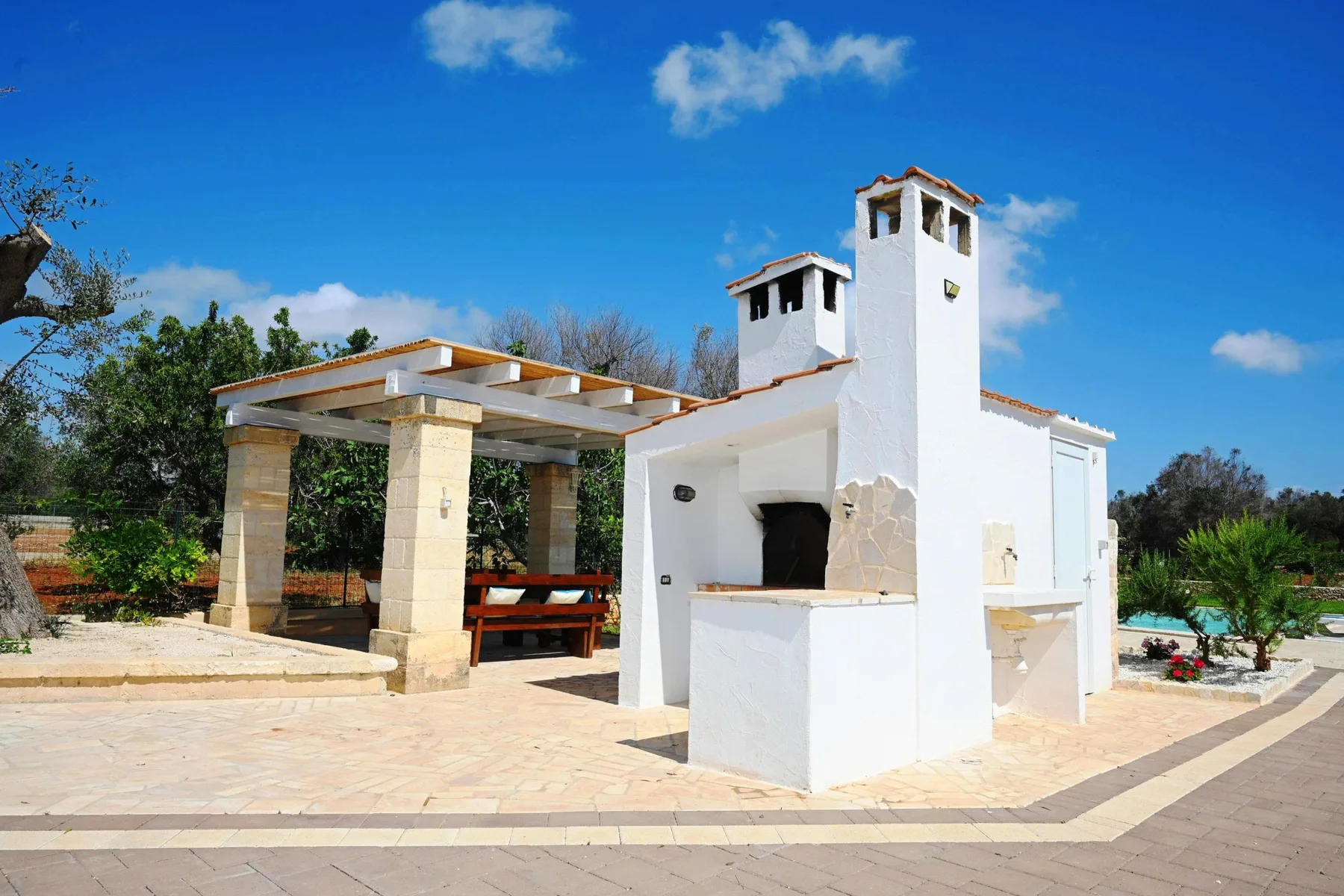 An outdoor courtyard with a white structure and a covered seating area.