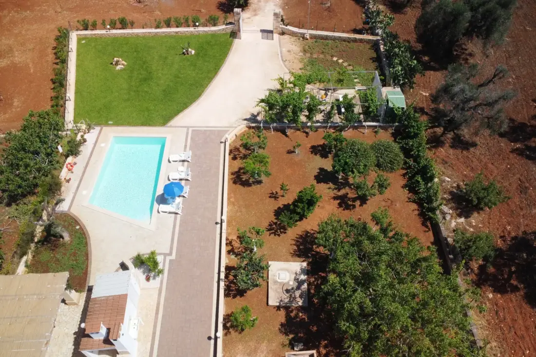 An aerial view shows an outdoor pool beside a landscaped garden.