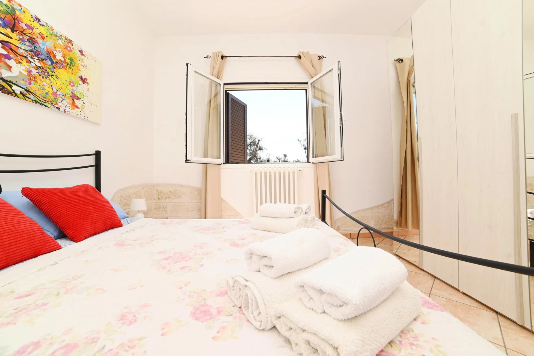 A bedroom with a bed, folded towels, and an open window.