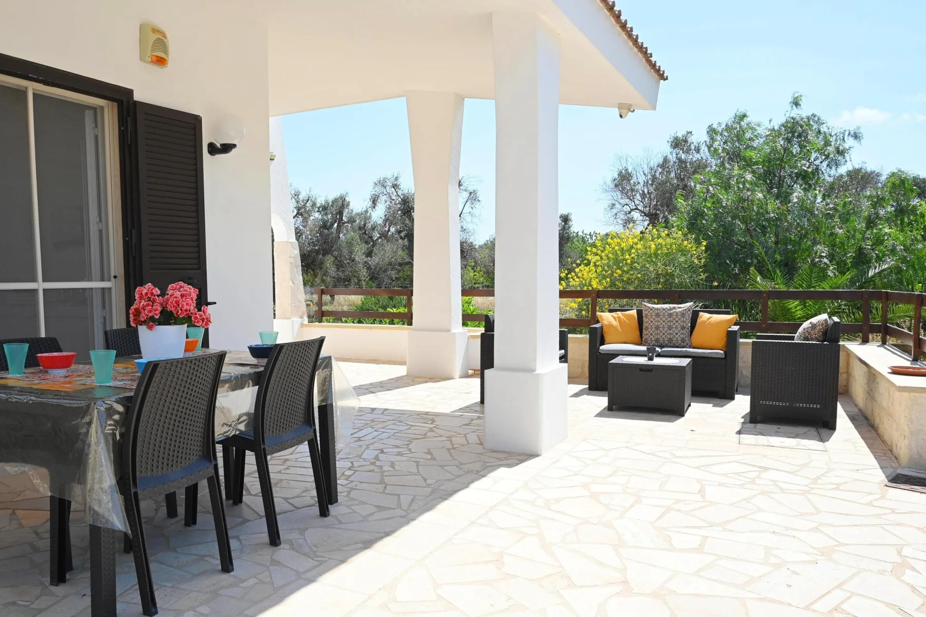 A sunny outdoor patio with a dining table and cushioned seating.