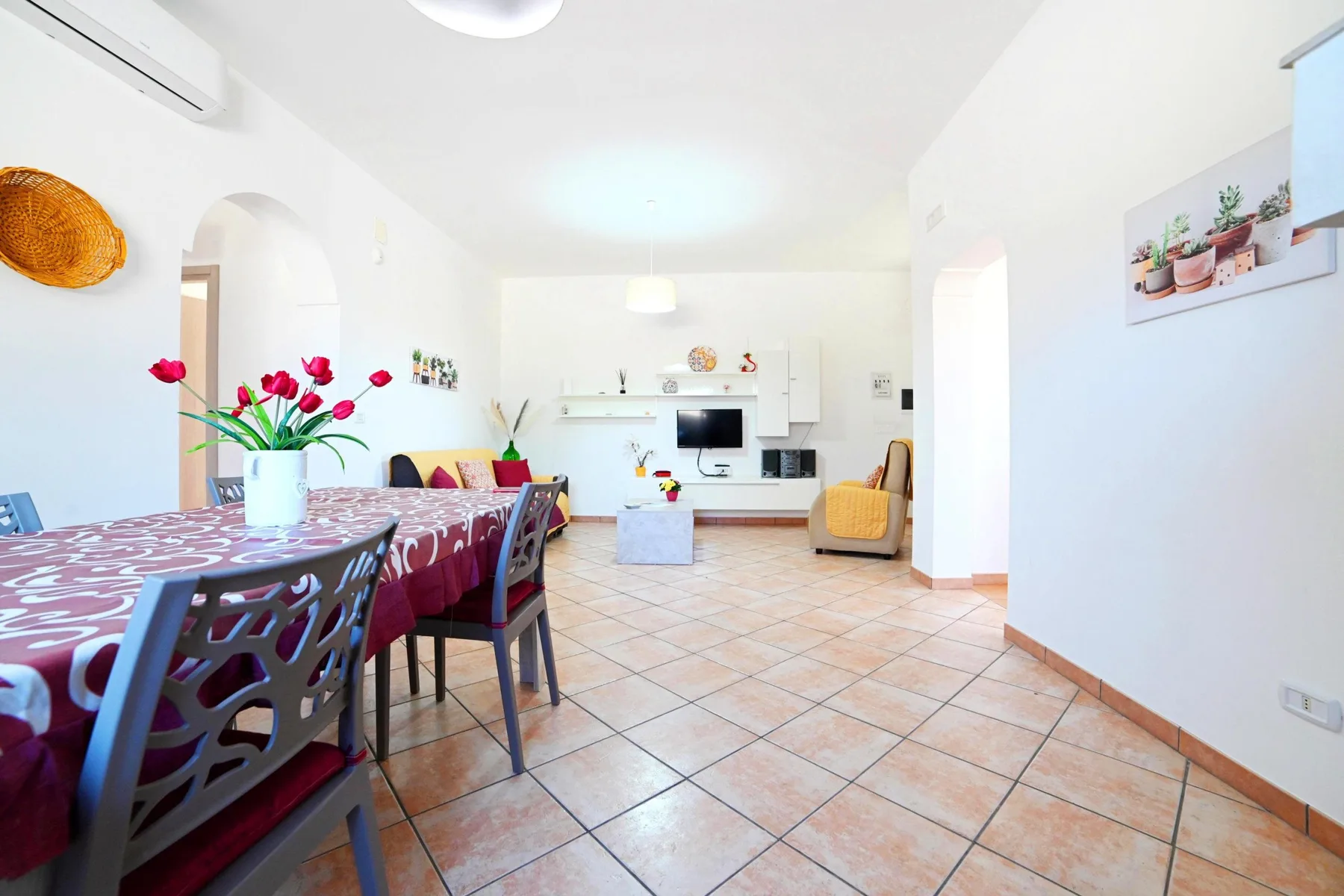 A bright open-plan living and dining room with a television and dining table.