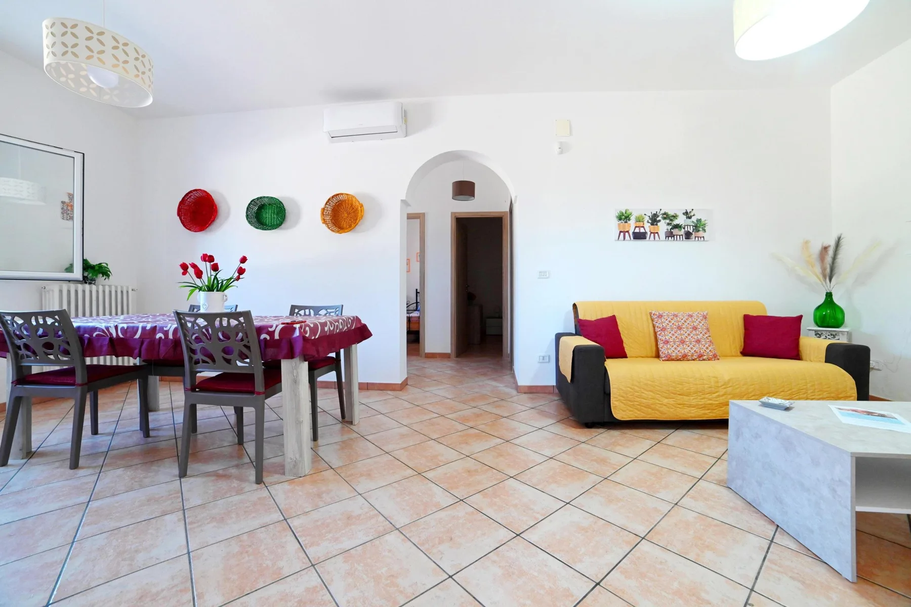 A bright living and dining room with a yellow sofa and a dining table.
