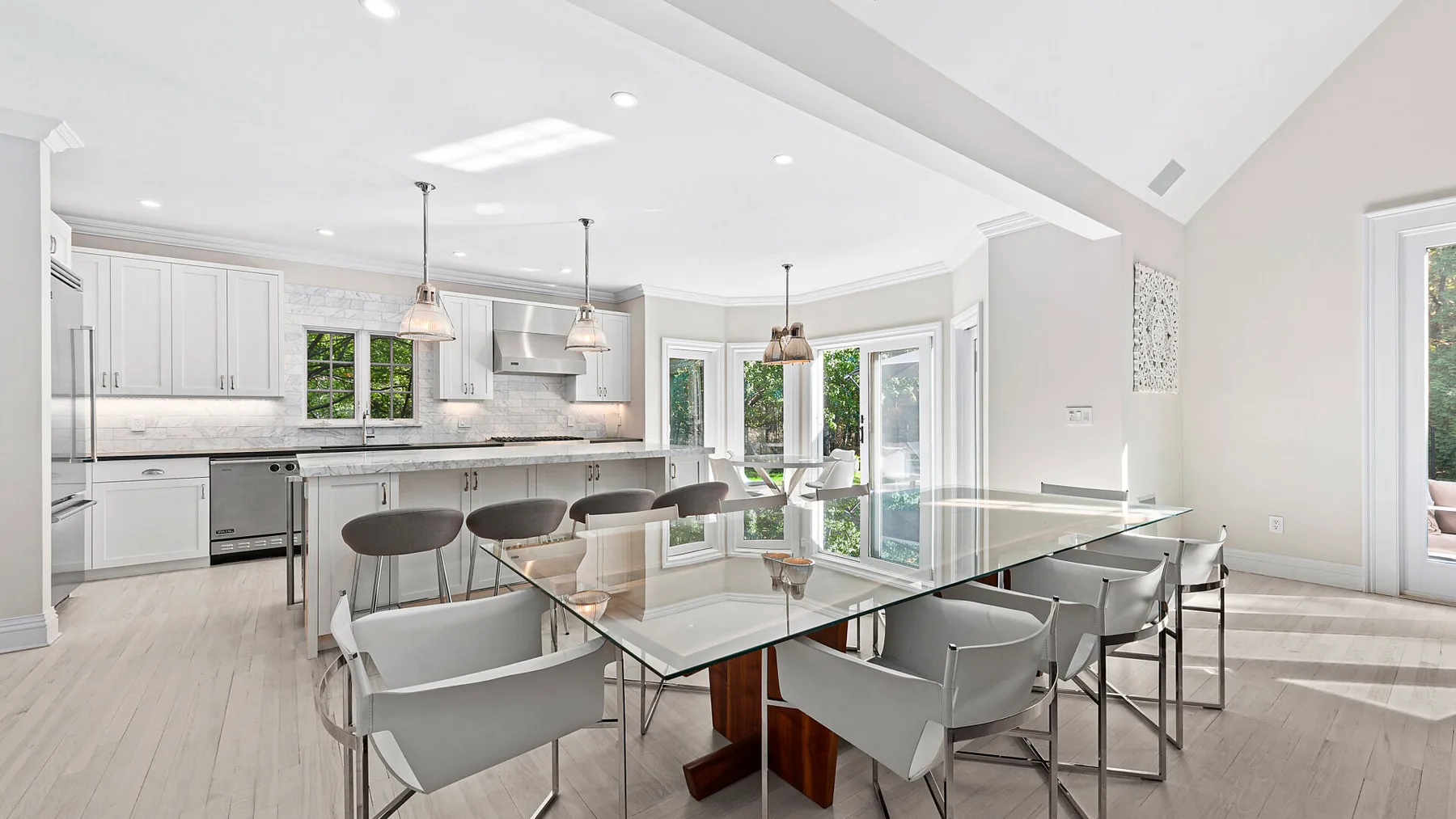Una luminosa cocina abierta al comedor, con una mesa de vidrio y asientos.