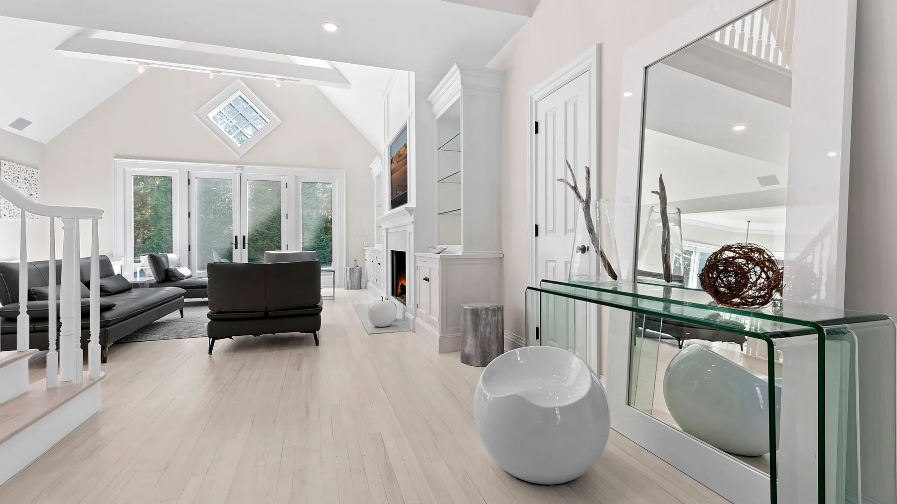 Una sala luminosa con asientos, ventanas altas y una mesa consola de vidrio.