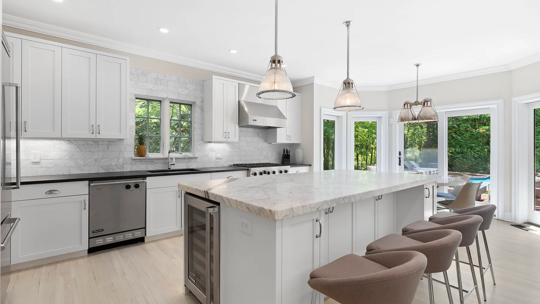 Una cocina luminosa con una isla grande y asientos junto a amplias ventanas.