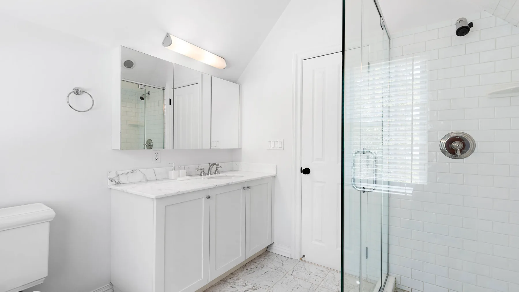 Un baño luminoso con un tocador largo y una ducha de vidrio.