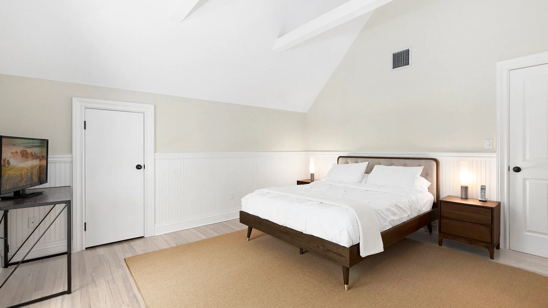 Un dormitorio luminoso con una cama tendida y mesitas de noche.