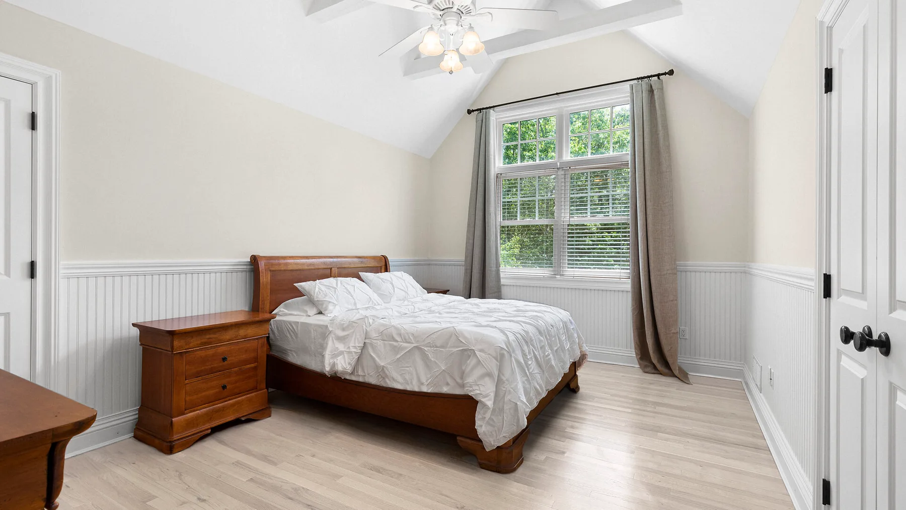 Un dormitorio luminoso con una cama bajo una ventana grande.