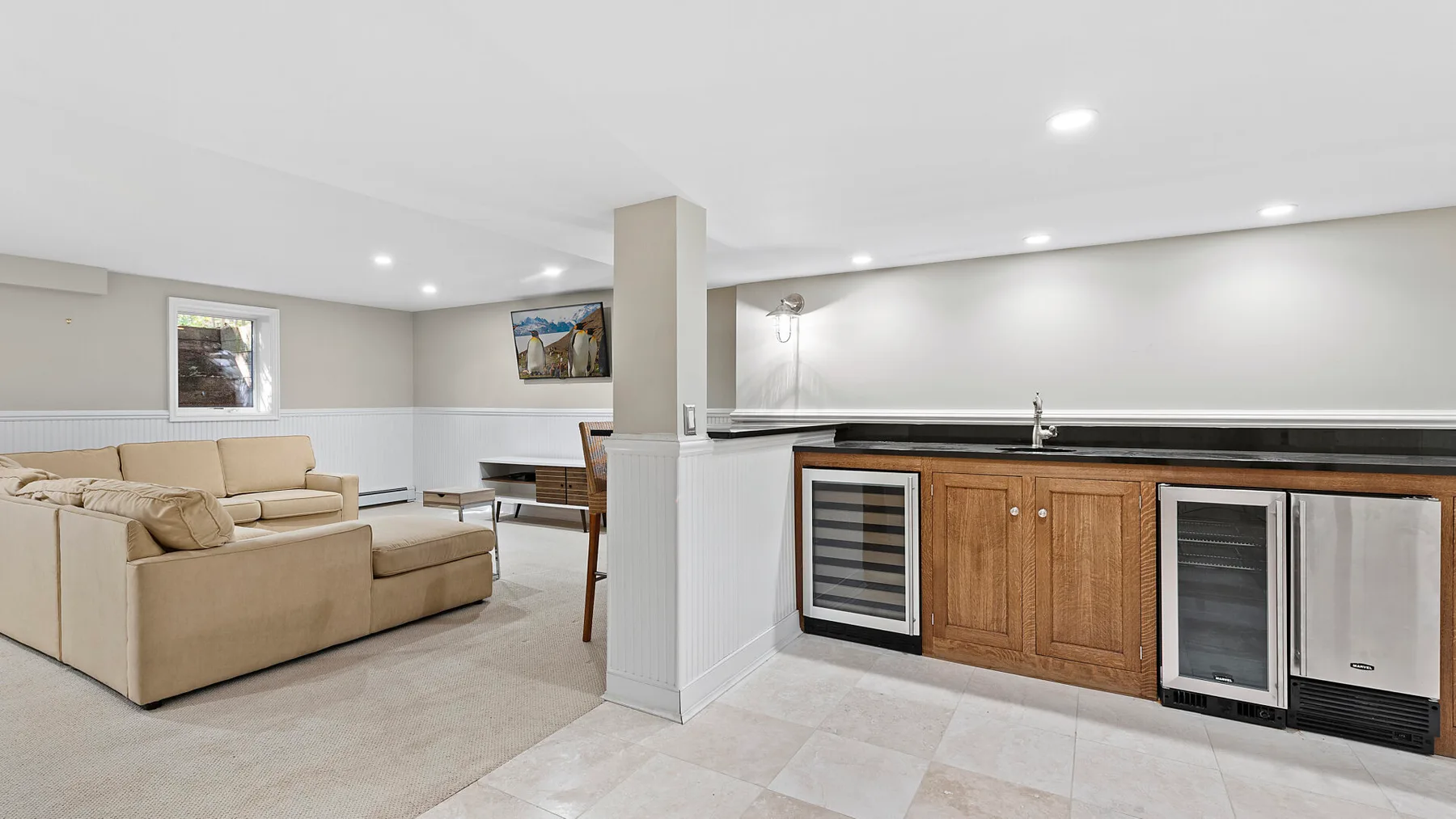 Una luminosa sala de estar y cocina diáfanas, con asientos beige y gabinetes de madera.