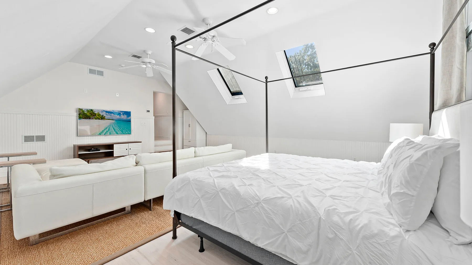Un dormitorio abuhardillado luminoso con una cama y una zona de estar separada.