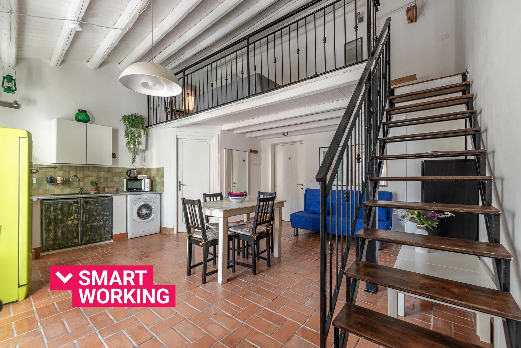 Una cocina y comedor con una mesa junto a una escalera abierta.