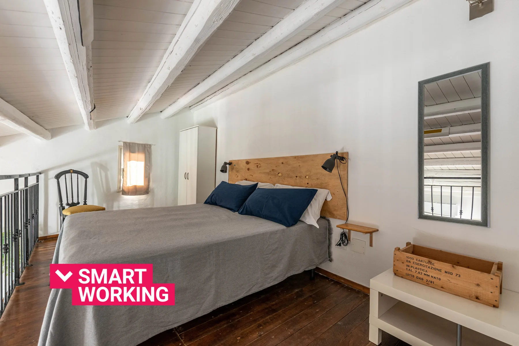 Un dormitorio con una cama grande, vigas expuestas en el techo y un espejo de pared.