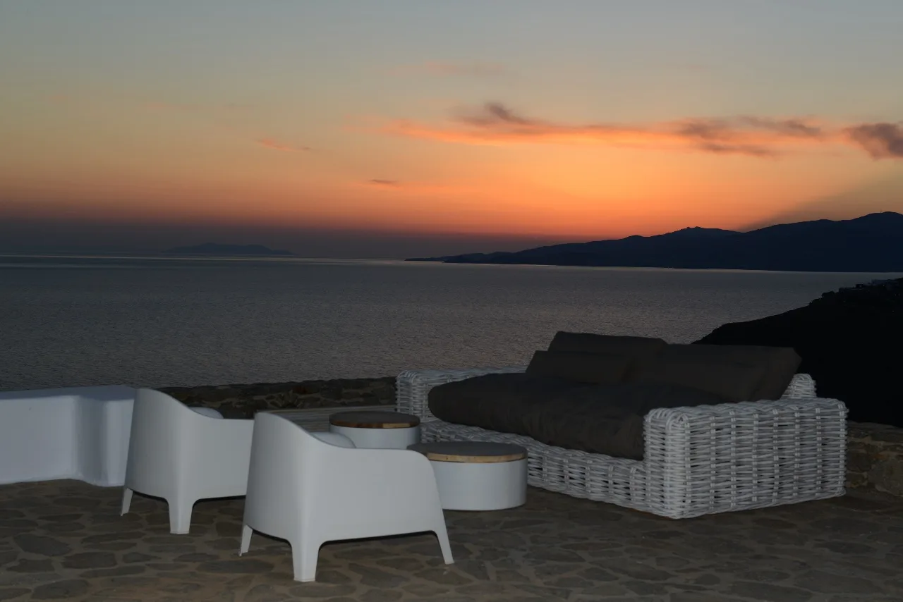 Outdoor seating overlooks the water at sunset.