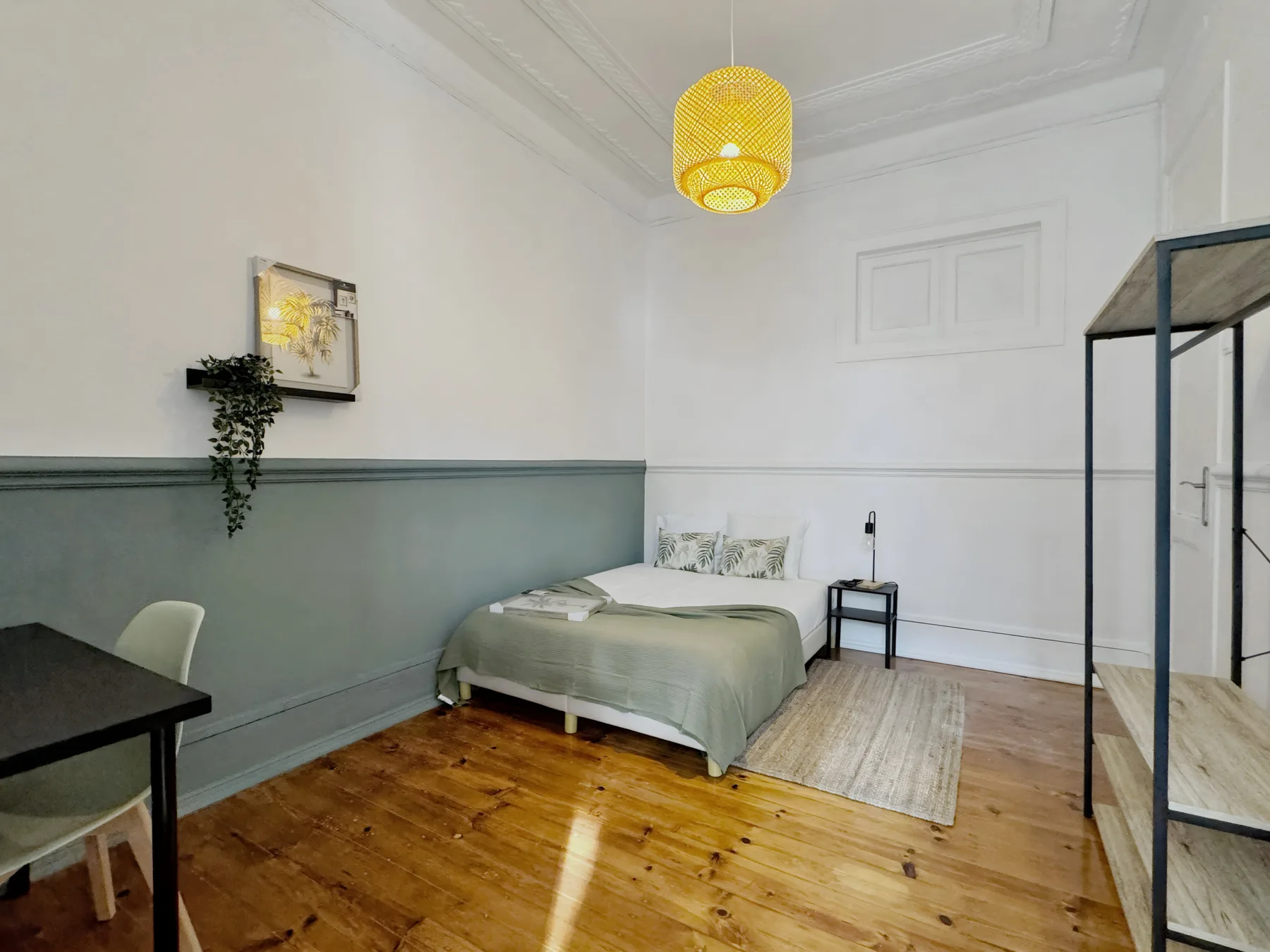 A bedroom with a bed, a small bedside table, and a desk.