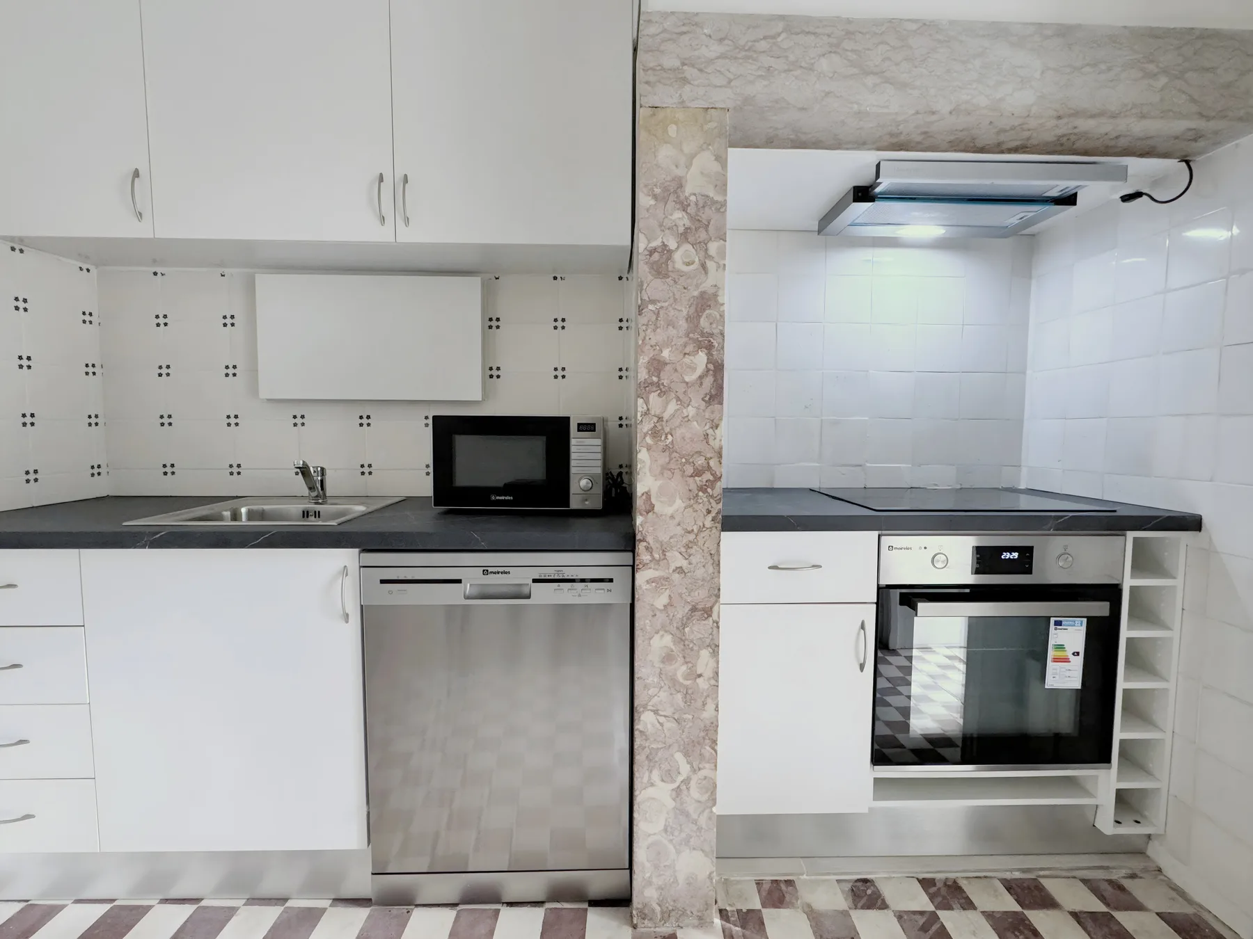 A compact kitchen with white cabinets, a sink, and built-in cooking appliances.