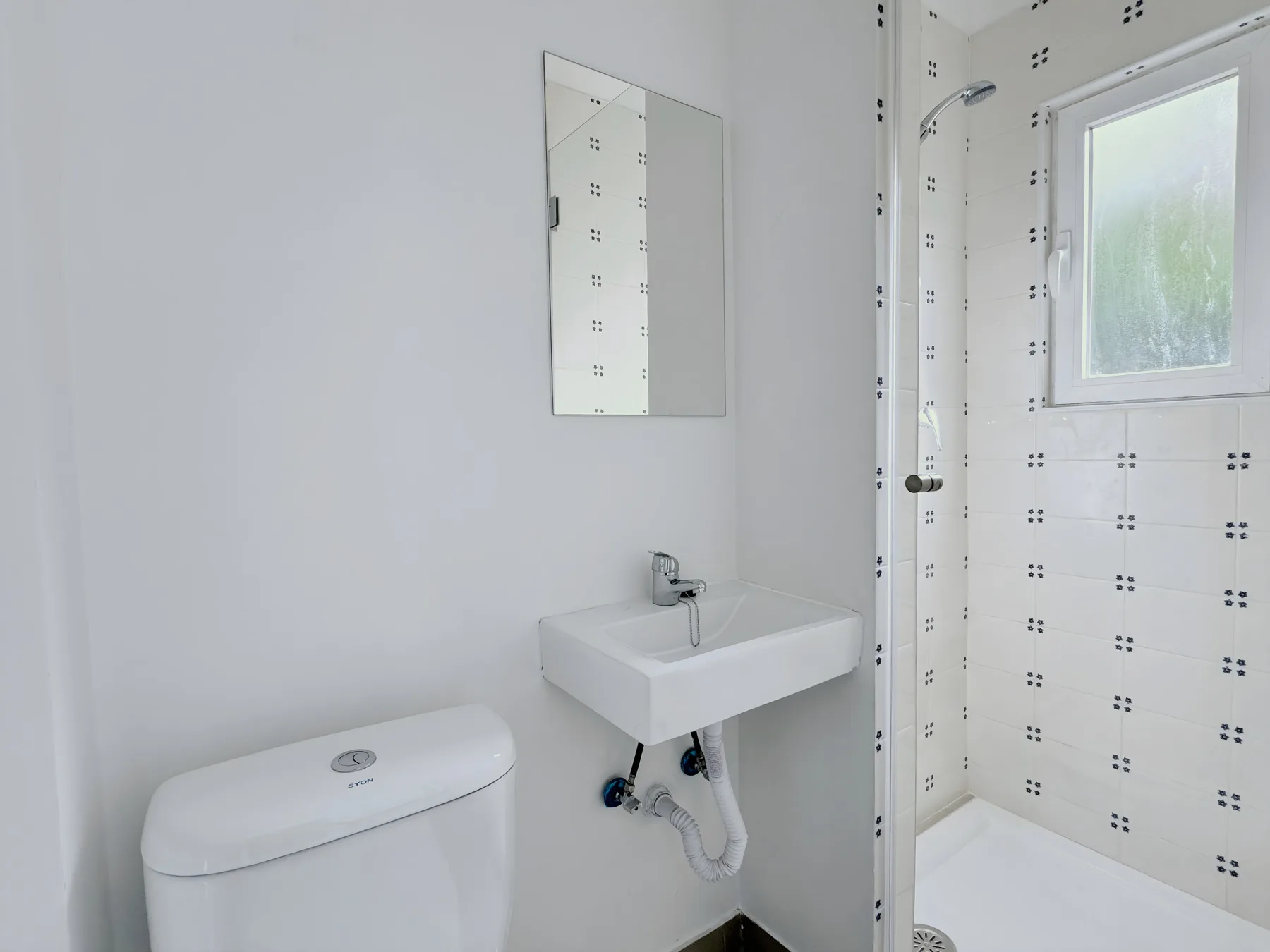 A bathroom with a wall-mounted sink and a shower.