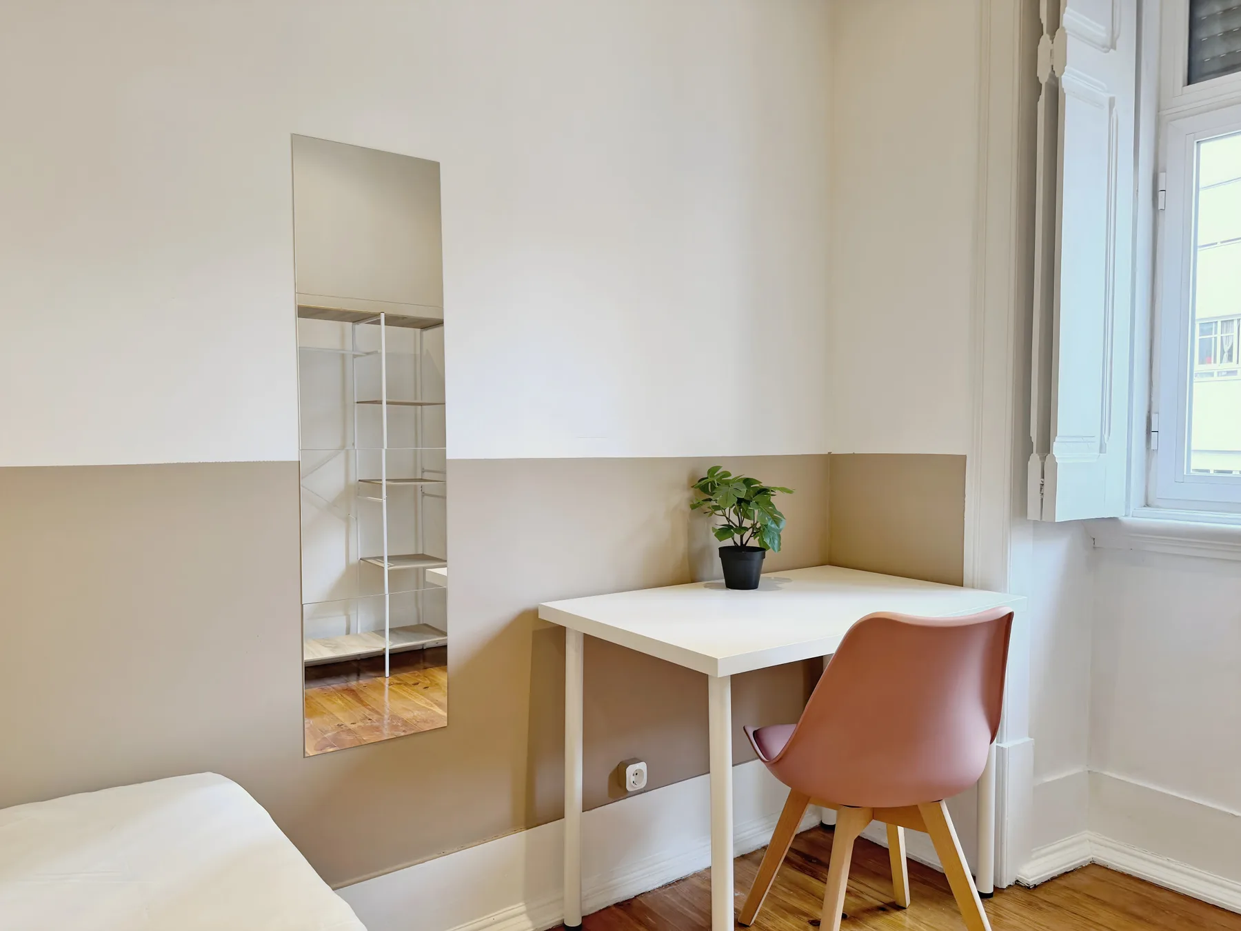 A bright room has a white desk, a pink chair, and a potted plant.