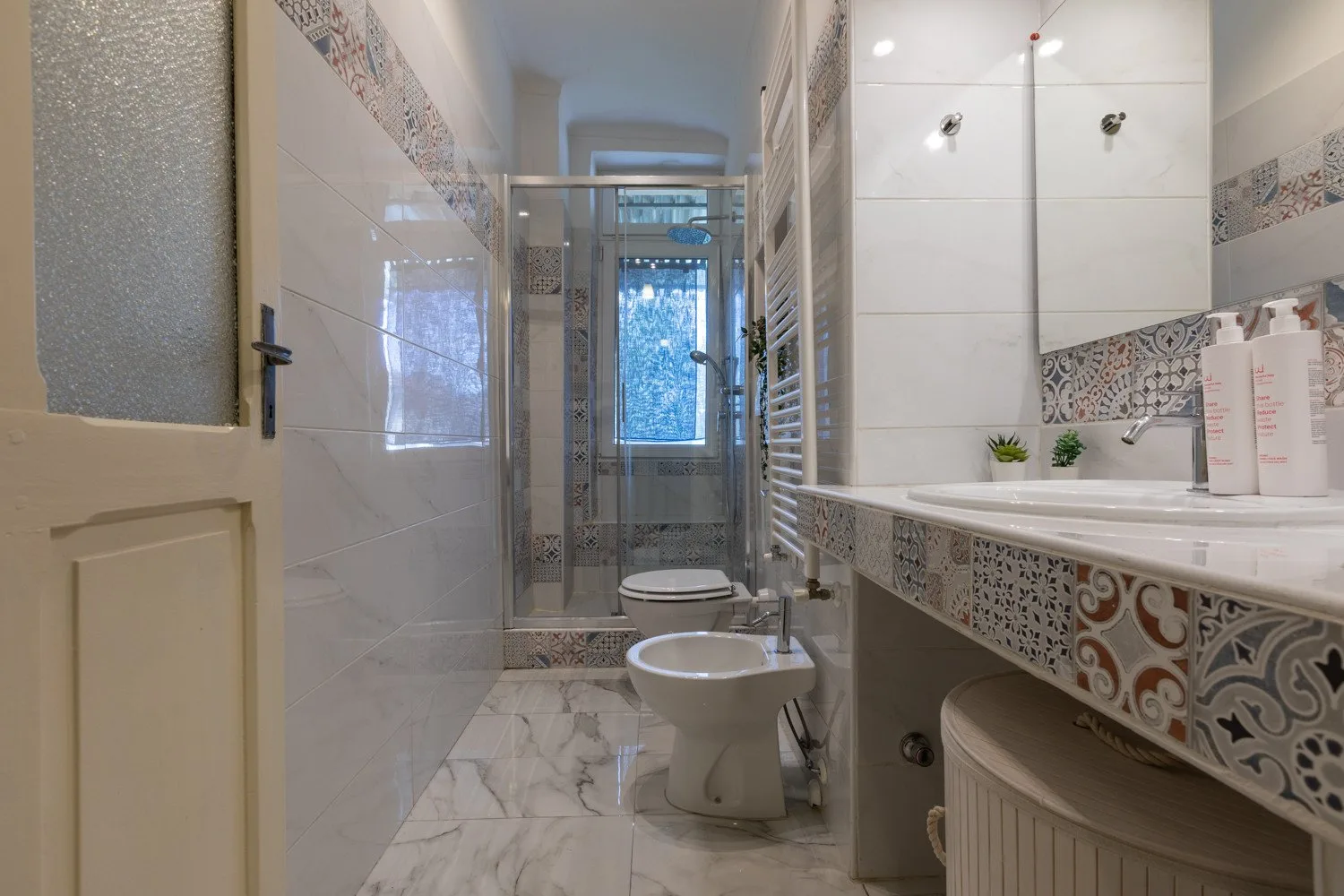Un baño con azulejos, lavabo, inodoro y ducha de vidrio.