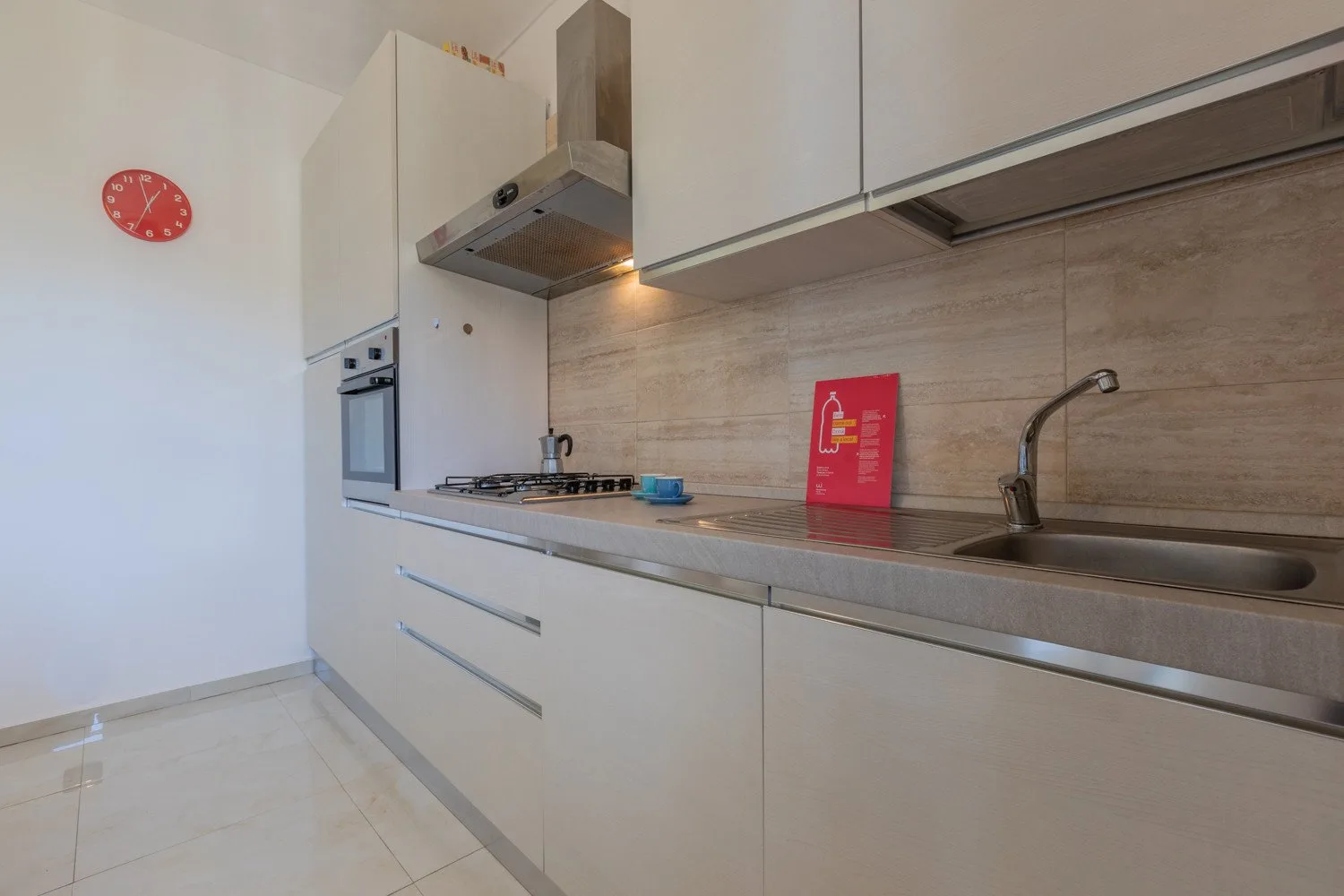 Una cocina moderna con armarios blancos, una placa de cocina y un fregadero.