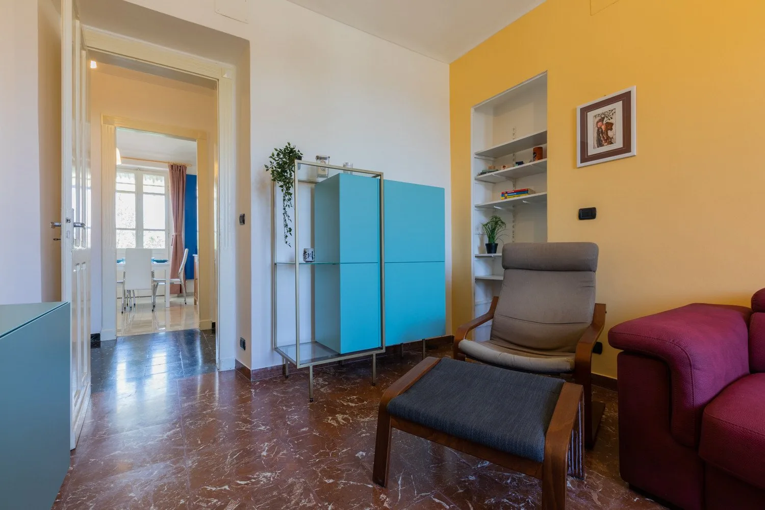 Una sala de estar con un sillón gris y un mueble azul.