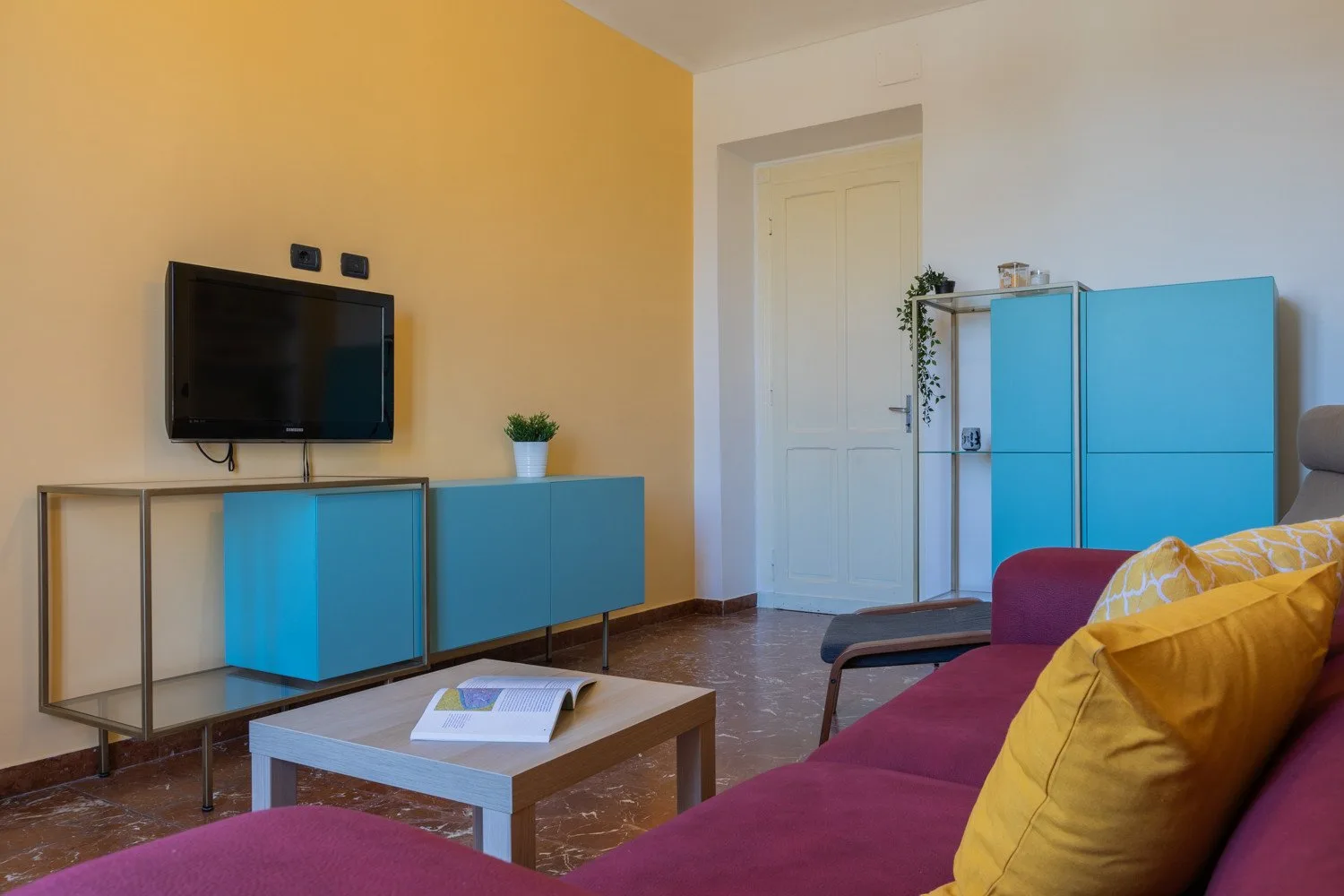 Una sala de estar con muebles azules, un televisor y asientos alrededor de una mesa de centro.