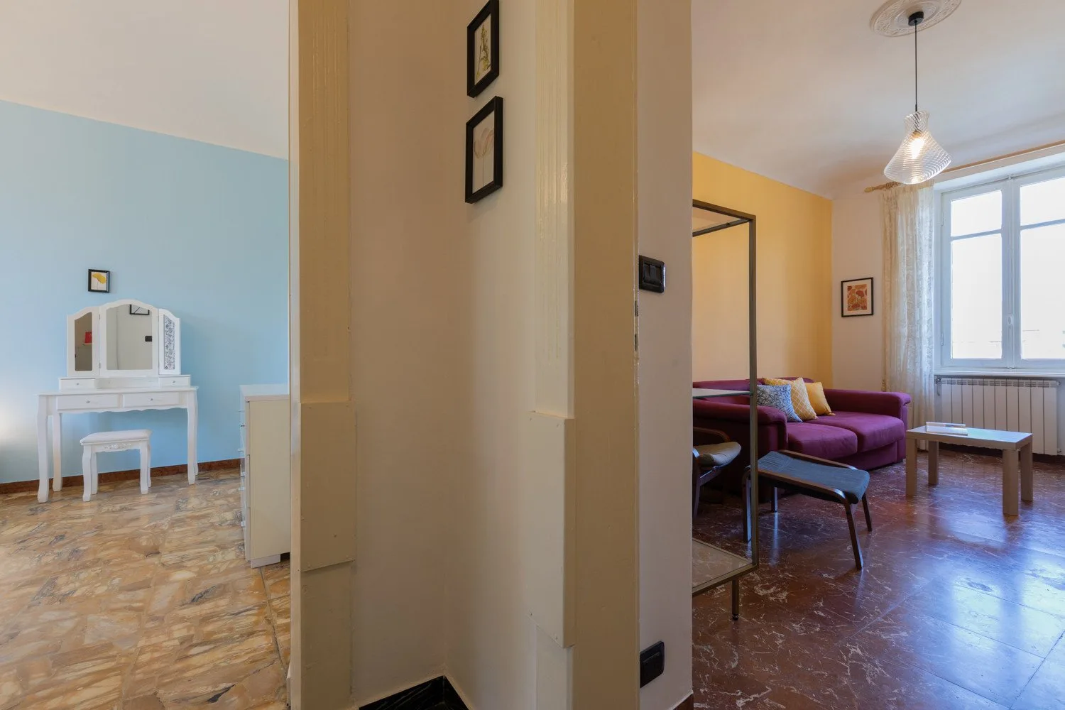 Una sala de estar con asientos morados y una mesa de centro está junto a un escritorio pequeño.