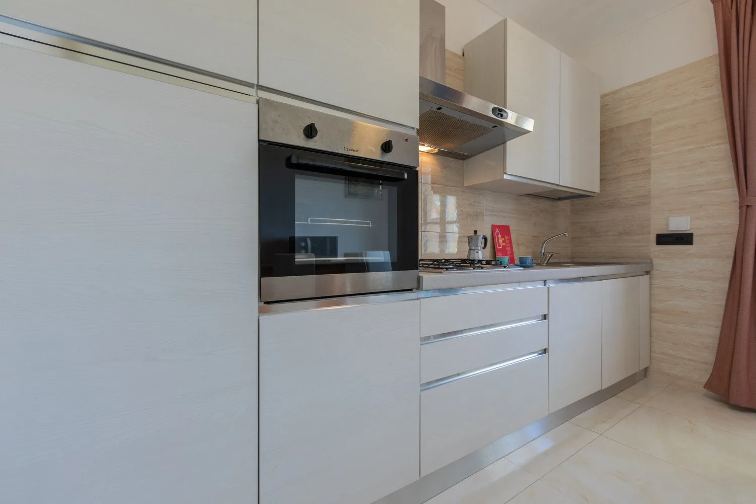 Una cocina moderna con gabinetes blancos, un horno y una encimera.
