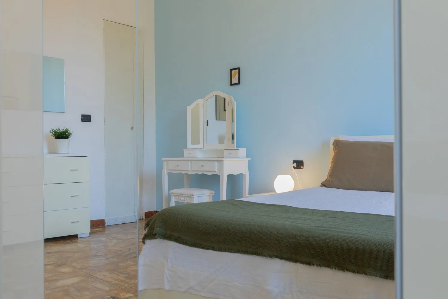 Un dormitorio con una cama y un pequeño tocador.