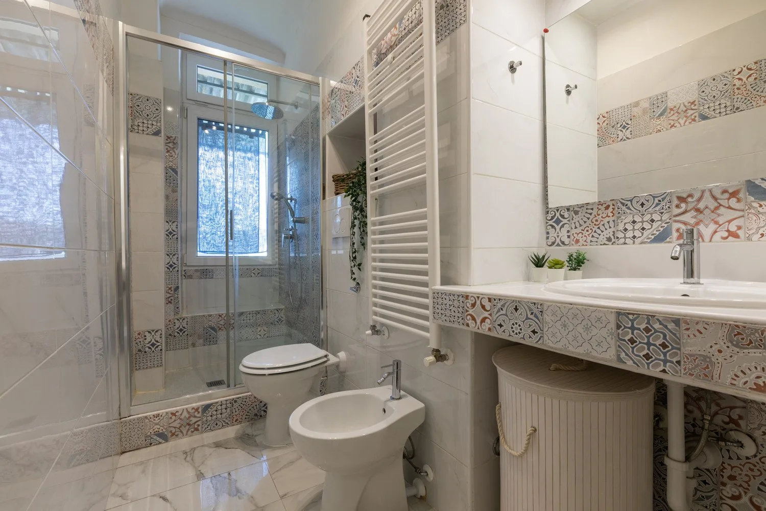 Un baño alicatado con ducha de cristal, inodoro y lavabo.