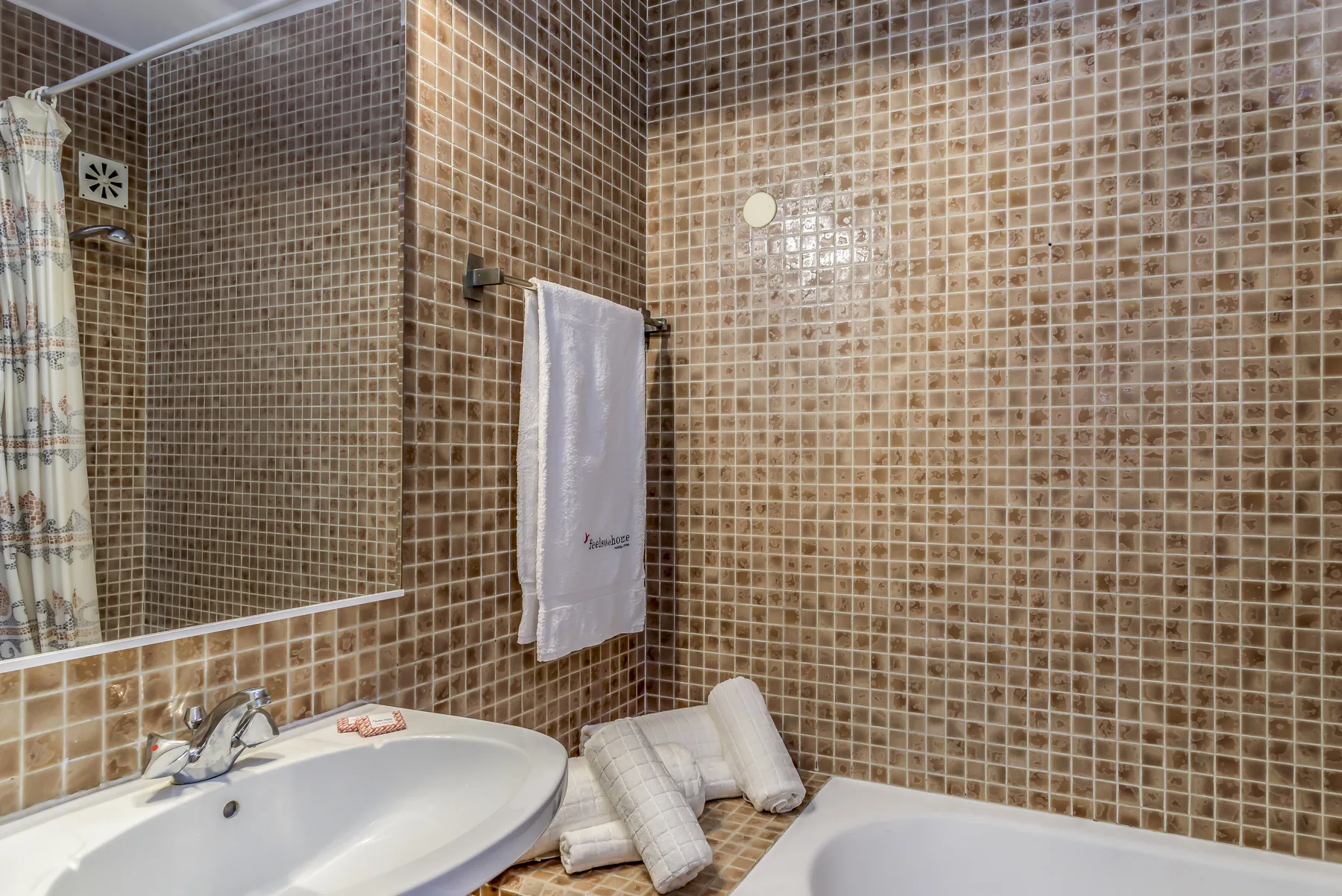Un baño alicatado con lavabo, bañera y toallas.