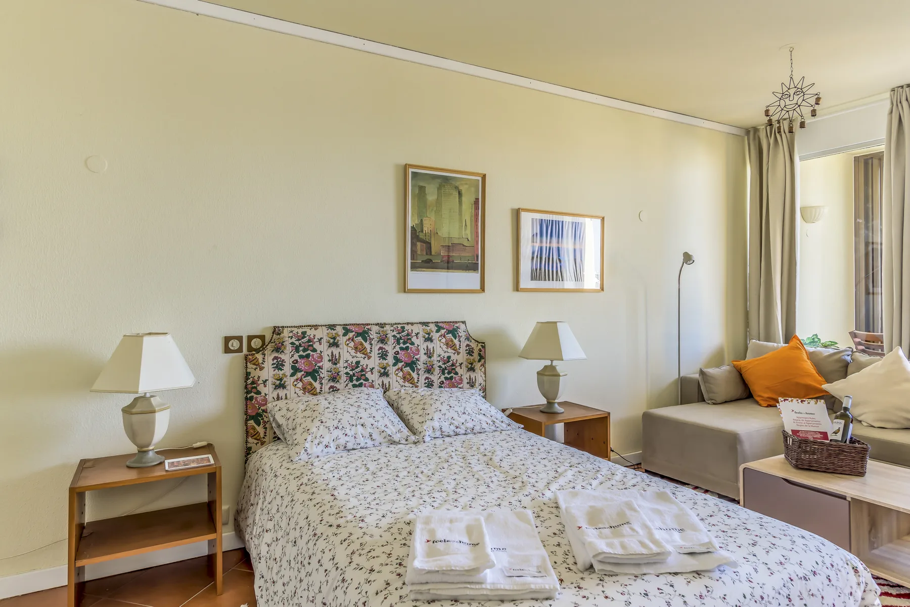 Un dormitorio con una colcha floral y asientos junto a la ventana.