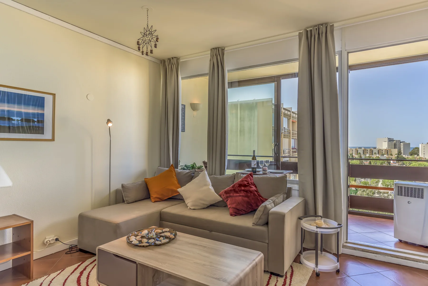 A living room with seating, a coffee table, and windows opening onto a balcony.