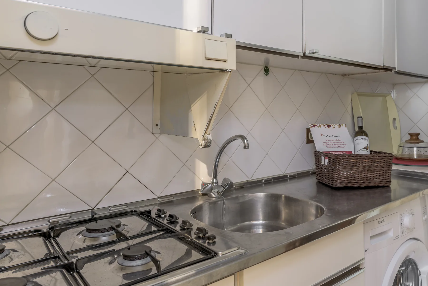 Kitchen counter with a stovetop, sink, and upper cabinets.