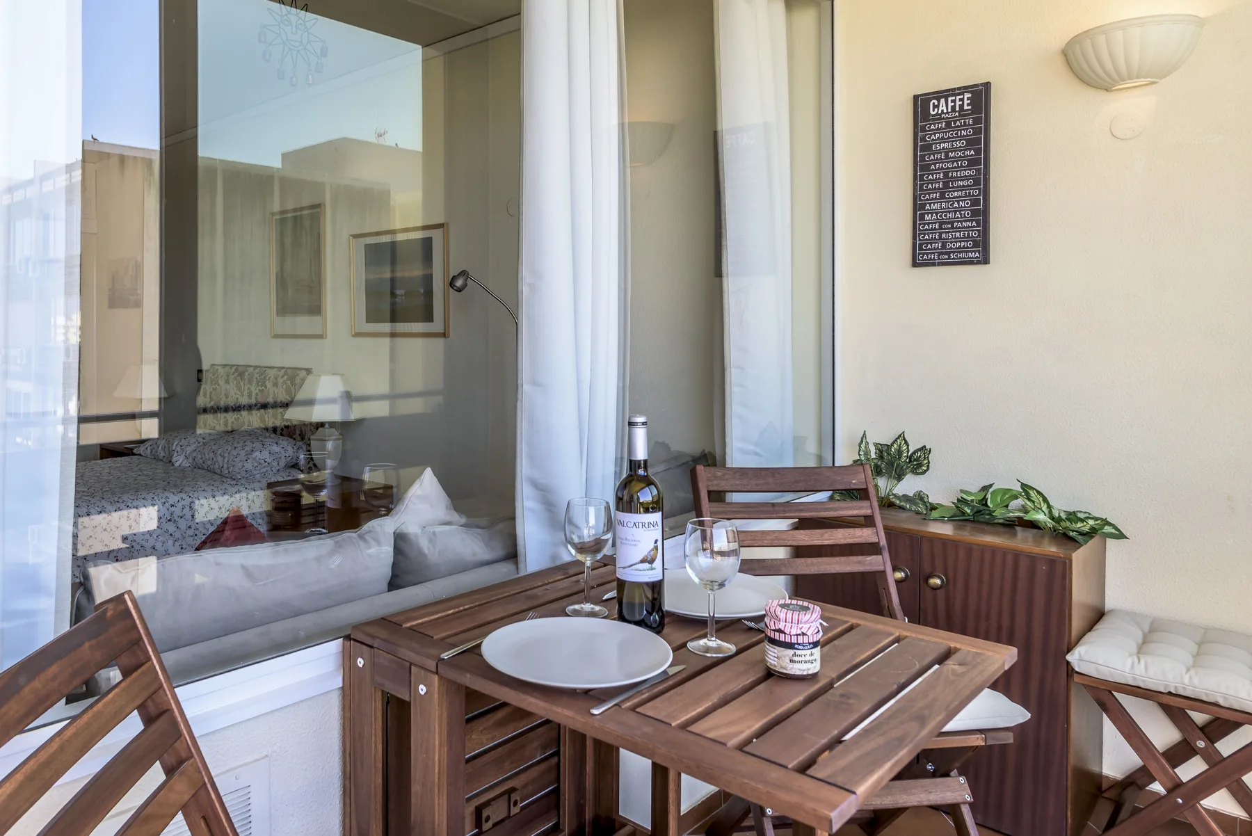 Un pequeño patio comedor con una mesa y sillas de madera junto a una ventana de cristal.