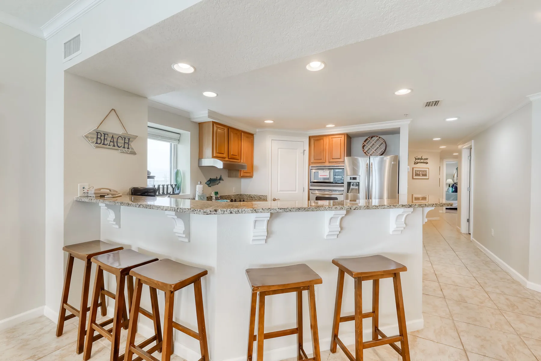 Una cocina luminosa con encimera de granito, gabinetes de madera y asientos de barra.
