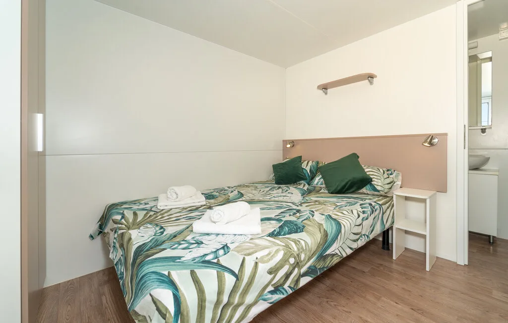 Un dormitorio con una cama doble cubierta con ropa de cama estampada en verde y azul.