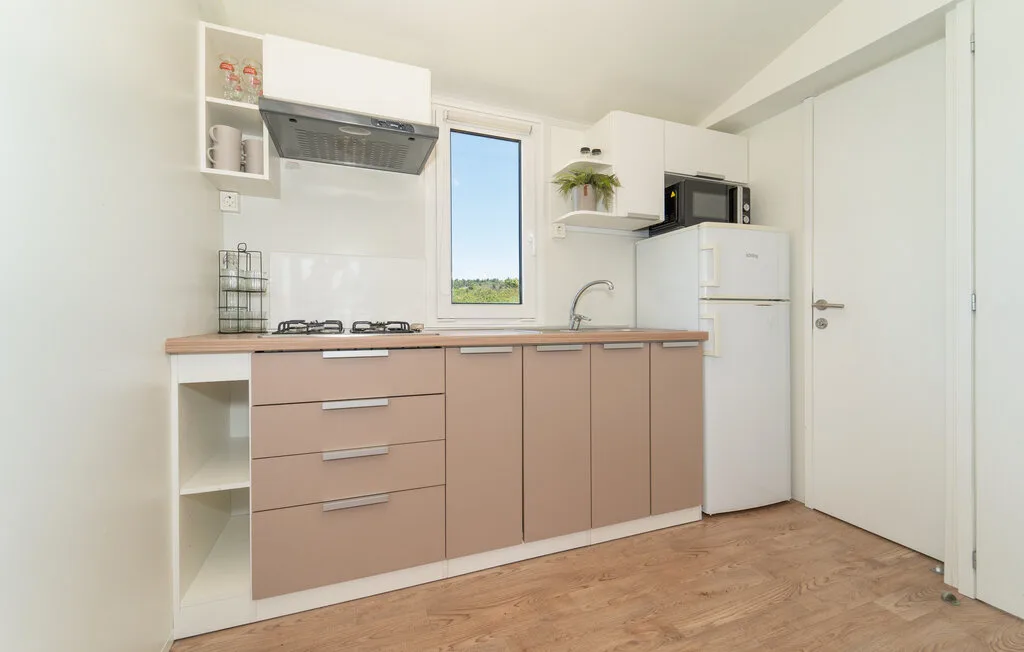 Una cocina luminosa con gabinetes claros, una encimera y una ventana.