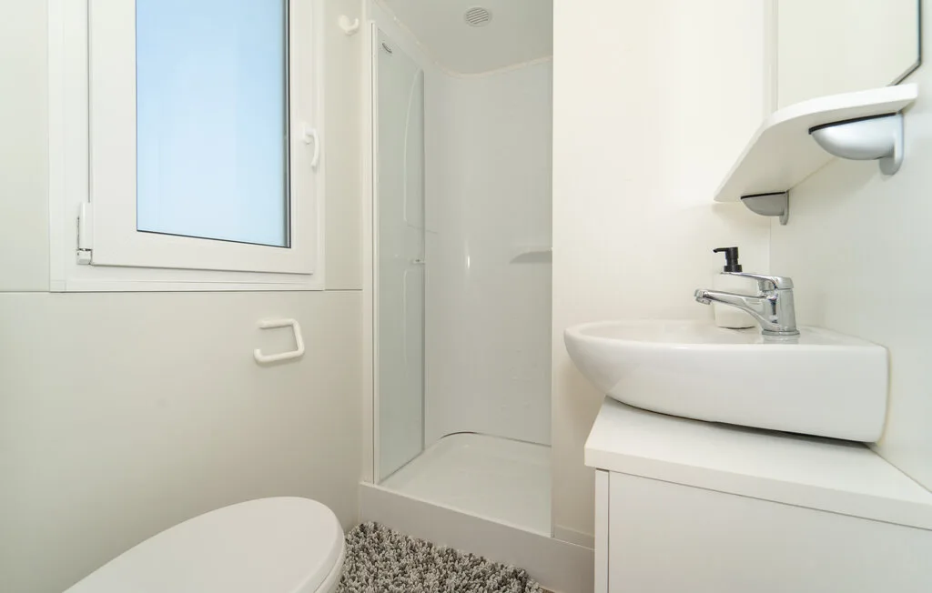 Un baño luminoso con lavabo, ducha y ventana.