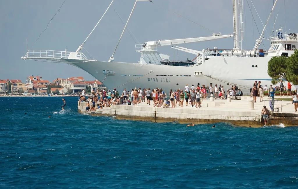 Un gran barco está atracado junto a un paseo marítimo concurrido.