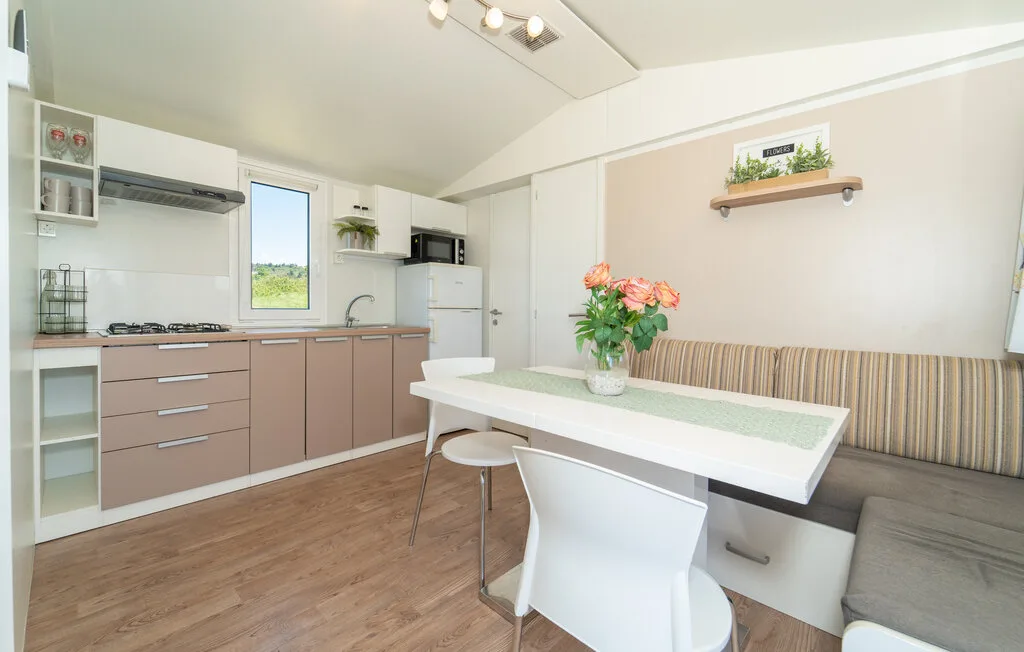 Una cocina luminosa con zona de comedor, mesa y flores.