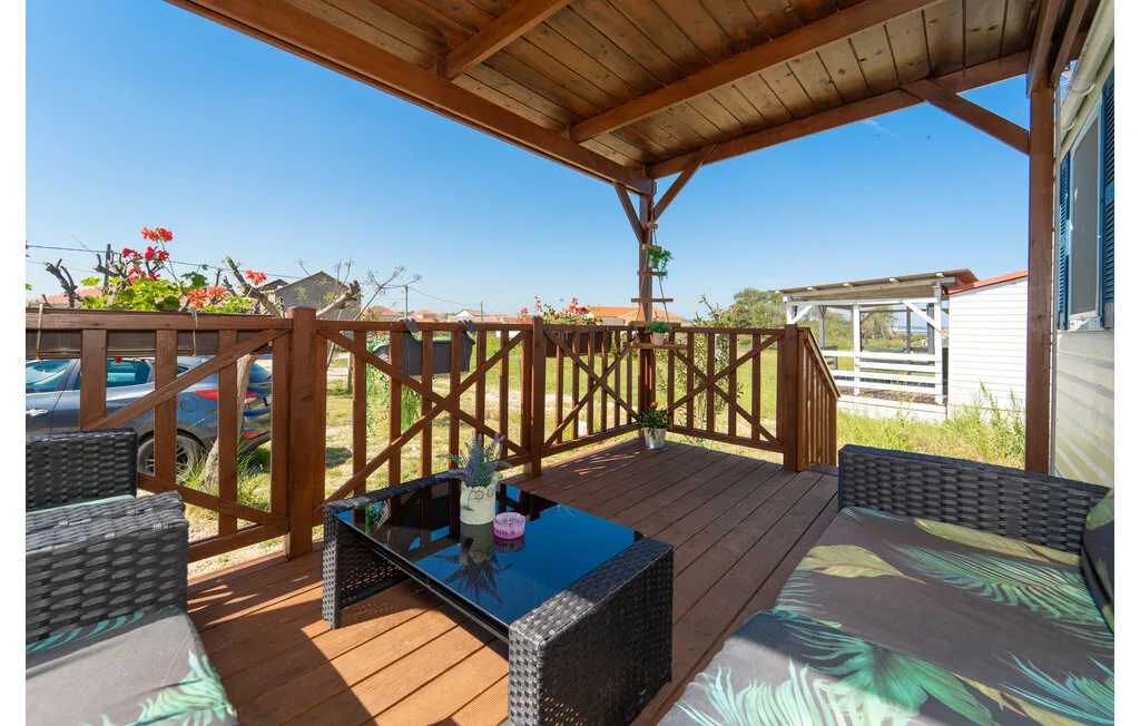 Una terraza de madera cubierta tiene asientos exteriores y una mesa baja.